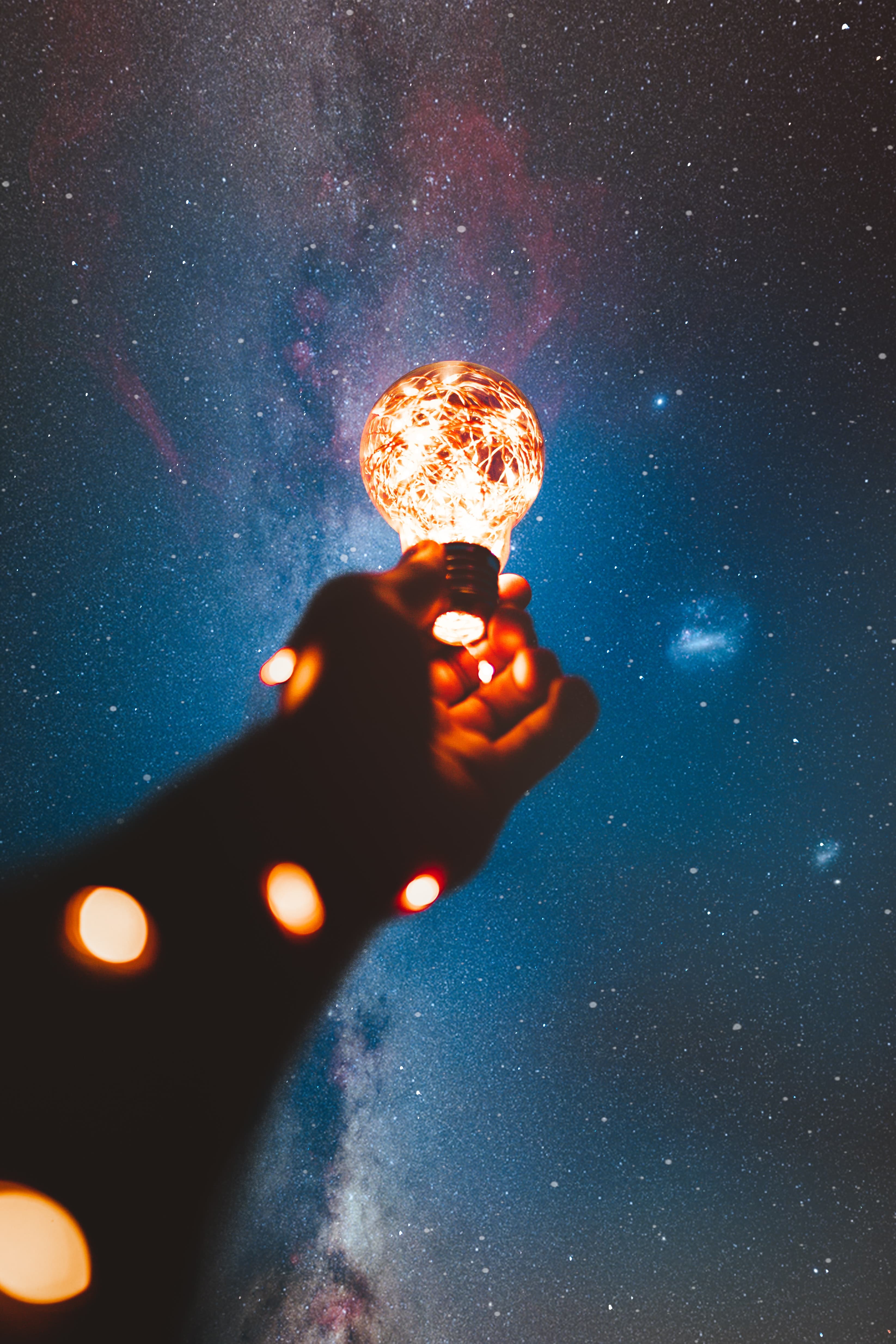 A hand cupping a small warm light against a dark sky